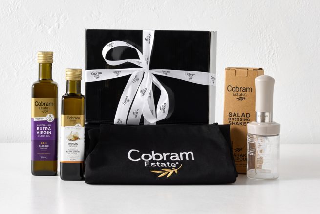 Cobram Estate extra virgin olive oil packaging set with Cobram Estate logo on black pouch, gift box and bottles, gold and white branding accents